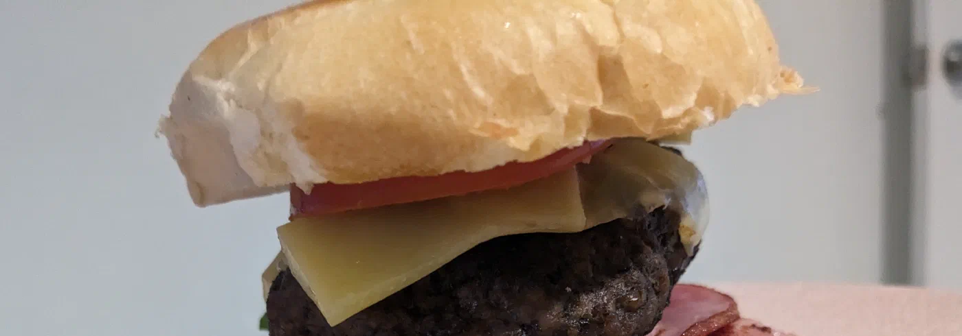 A stacked burger with melted cheese and salad on a plate