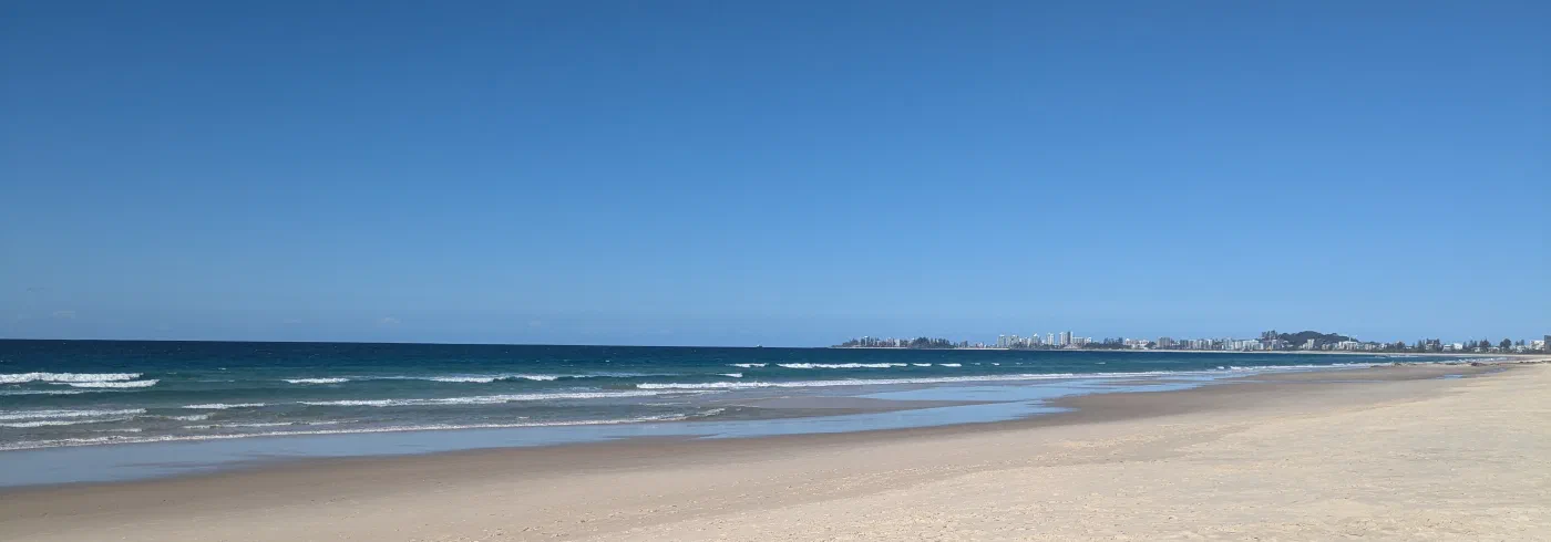 An empty sandy beach stretching toward a distant coastal skyline